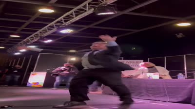 خافيير ميلي يصعد على خشبة المسرح ويظهر بجواره رجل يحمل شوفار ويرتدي شال صلاة يهودي، أغسطس 2023